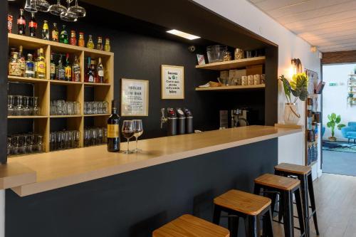 a bar with two stools and a counter with wine glasses at Clarion Aparthotel Toulouse Le Parc de l'Escale in Toulouse
