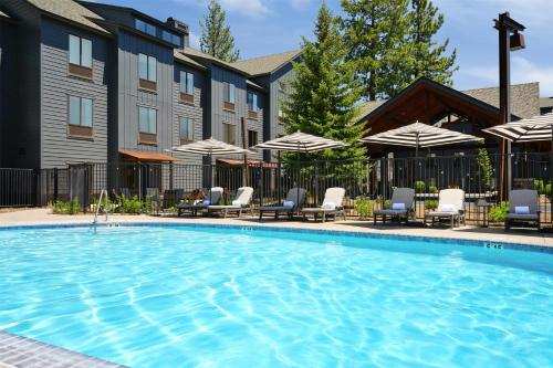 a swimming pool at a hotel with chairs and umbrellas at Martis Valley Lodge, Tapestry Collection by Hilton in Truckee