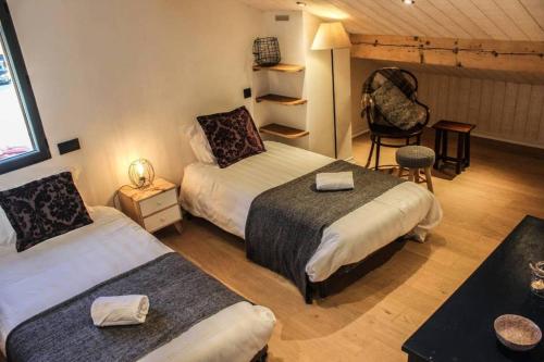 a hotel room with two beds and a chair at Chalet Petit Pierre Les Gets - Mountain Voyages in Les Gets