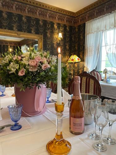 a table with a candle and a vase with flowers at Rezydencja Grawert Boutique & Spa in Lądek-Zdrój