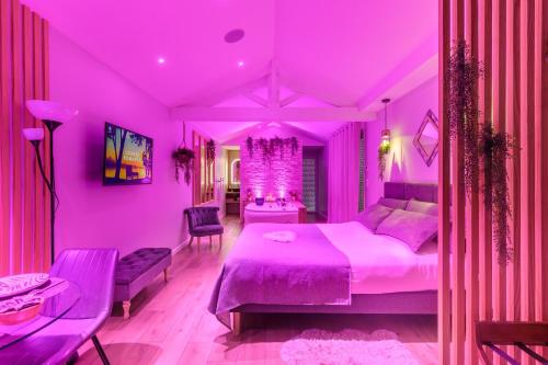 a pink bedroom with a bed and a table at L'Essentiel - Love 5 Etoiles in Talmont
