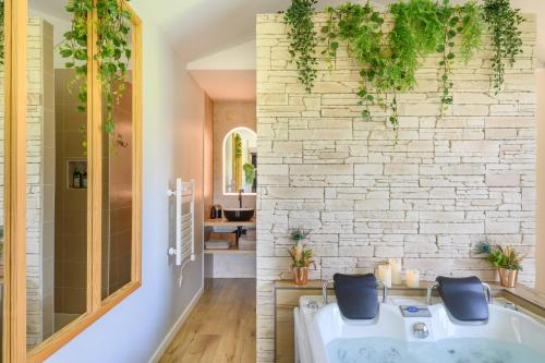 a bathroom with a tub and a stone wall at L'Essentiel - Love 5 Etoiles in Talmont
