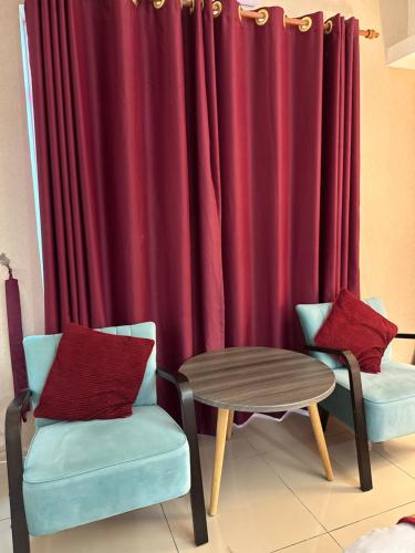a room with two chairs and a table and a red curtain at The Viana Apartment 1 in Kota Bharu