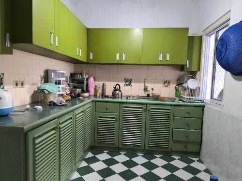 a kitchen with green cabinets and a checkered floor at Villa Narendra Yogyakarta in Kaliurang