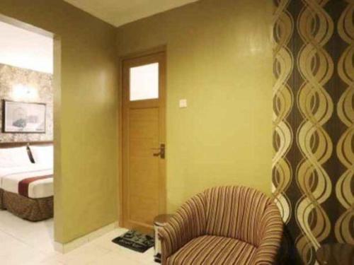 a bedroom with a bed and a chair in a room at Hotel Permata Bandara in Jakarta