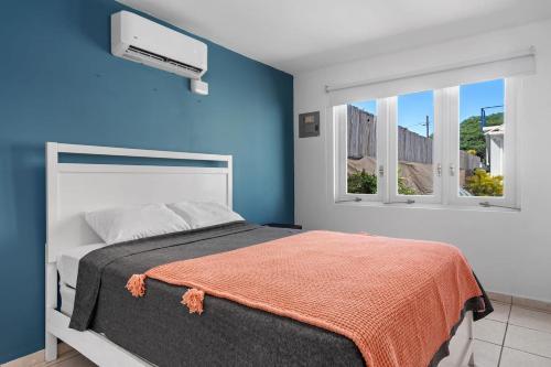 a bedroom with blue walls and a bed with an orange blanket at Nice Pool Near The Beach Free Local Coffee in San Juan