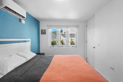 a bedroom with a bed with an orange blanket at Nice Pool Near The Beach Free Local Coffee in San Juan