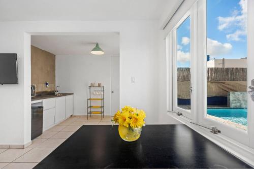 a kitchen with a vase with yellow flowers on a table at Nice Pool Near The Beach Free Local Coffee in San Juan