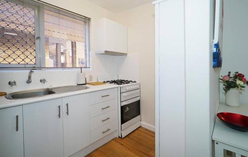 a white kitchen with a stove and a sink at Rivervale Cosy Stunner Sleeps 2 in Perth