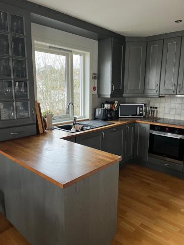 Una cocina con gabinetes negros y una encimera de madera. en Sentral og romslig bolig, en Stord