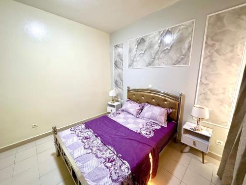 a bedroom with a bed with purple sheets and pillows at Appartement Duplex in Dakar