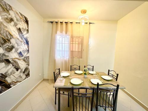 a dining room with a table with chairs and a painting at Appartement Duplex in Dakar