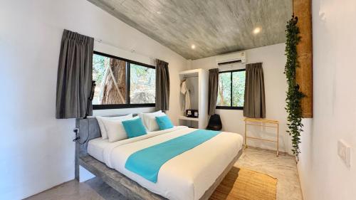 a bedroom with a large bed with blue and white pillows at Pahili Pool Villas Koh Tao - SHA Plus in Koh Tao