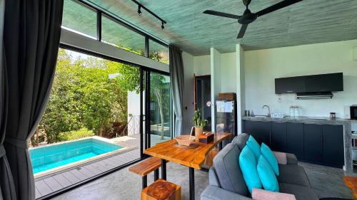 a living room with a table and a swimming pool at Pahili Pool Villas Koh Tao - SHA Plus in Koh Tao