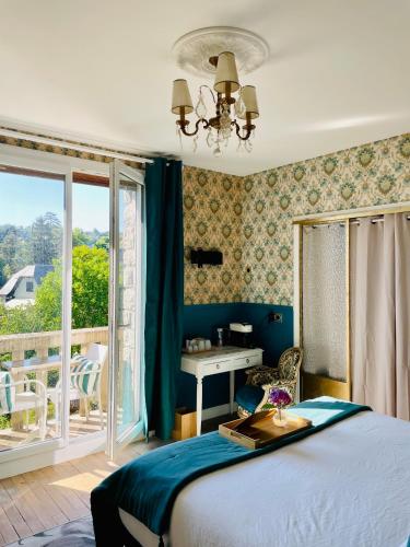 a bedroom with a bed and a desk and a window at La Maison au toit vert in Espalion