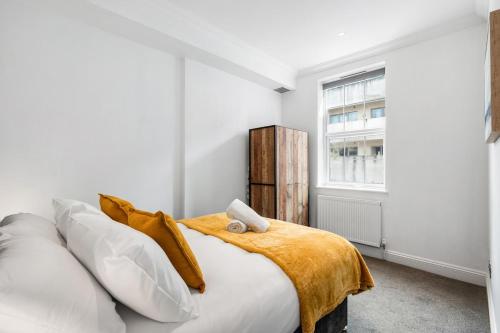 a bedroom with a bed with a yellow blanket and a window at Silva Getaway Central Brighton in Brighton & Hove