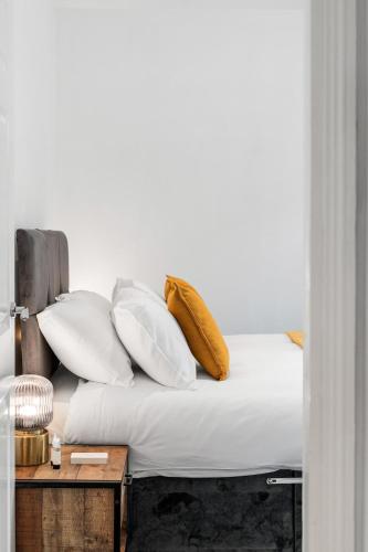 a bed with white pillows and a wooden table at Silva Getaway Central Brighton in Brighton & Hove