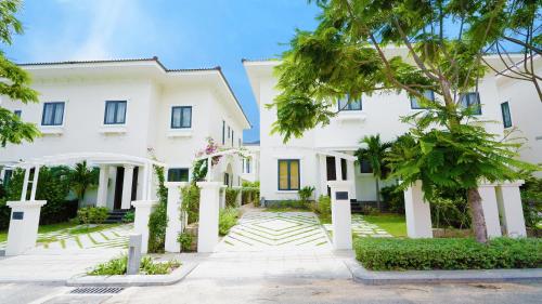 an exterior view of a white house with trees at Swiss-Belvillas Solavita Binh Tien in Binh Tien