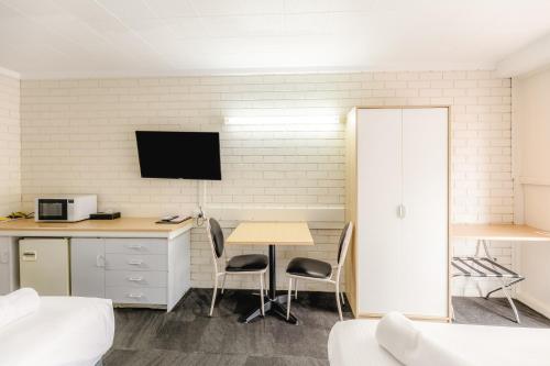 a room with a table and a tv on a wall at Wanderlight Motor Inn in Mudgee