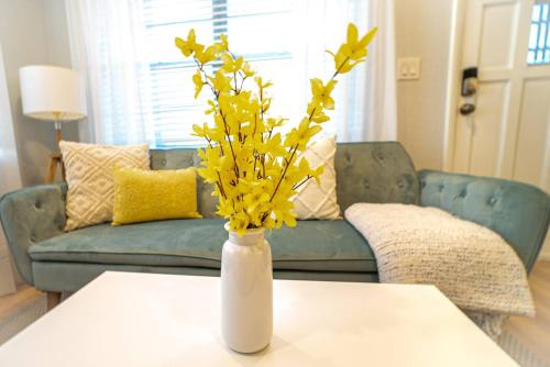 a white vase with yellow flowers on a table at Chic & Stylish Central location in Tampa