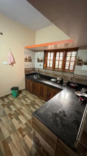 a kitchen with a black counter top and wooden floors at Podanolana residency- Sleep Above the Clouds in Madikeri