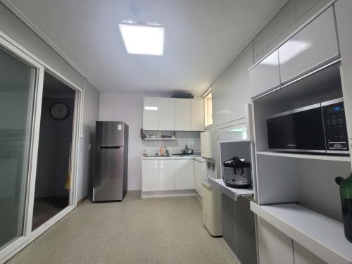 a kitchen with white cabinets and a stainless steel refrigerator at Seogwipo Seoul Hotel in Seogwipo