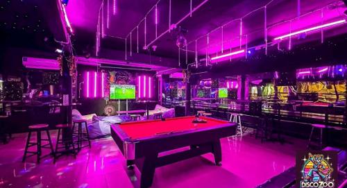 a ping pong table in a room with pink lighting at DISCO ZOO Bar & Hostel in Haad Rin