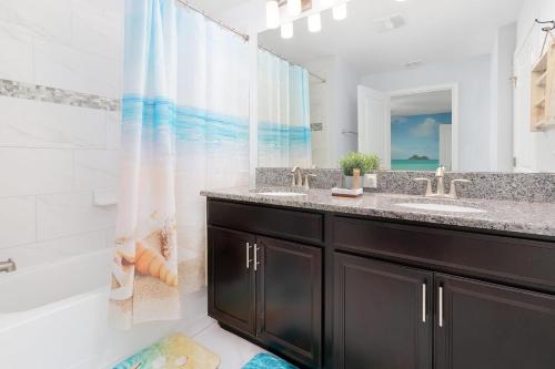 Un baño con lavabo, bañera y ducha. en Bright townhouse near Disney w pool & grill, en Kissimmee
