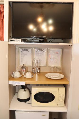 a small kitchen with a microwave and a tv at Victoria Manor in Upington