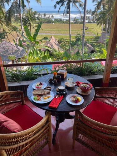 Supersenang Boutique Resort Balian في Balian: طاولة مع أطباق من الطعام فوق شرفة