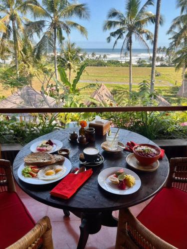 Supersenang Boutique Resort Balian في Balian: طاولة عليها طعام مطلة على المحيط