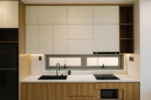 a kitchen with white cabinets and a sink and a window at Tuberose - Victoria Villa in Dien Ban