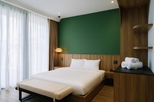 a bedroom with a bed and a green wall at Tuberose - Victoria Villa in Dien Ban