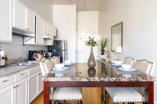 a kitchen with a table with a vase of flowers on it at Greely Gaslamp - Loft W Parking & 3 Beds #302 in San Diego