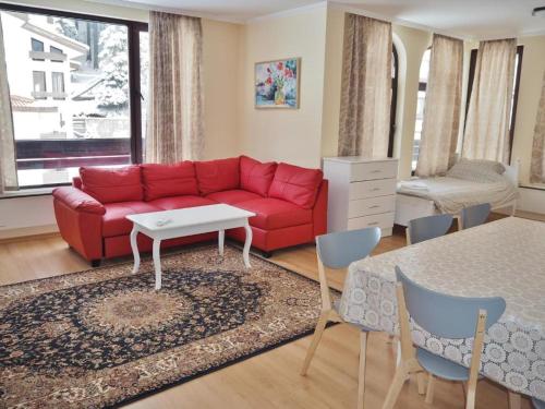 a living room with a red couch and a table at Elit Pamporovo Apartments in Pamporovo