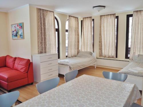 a living room with a red couch and a bed at Elit Pamporovo Apartments in Pamporovo