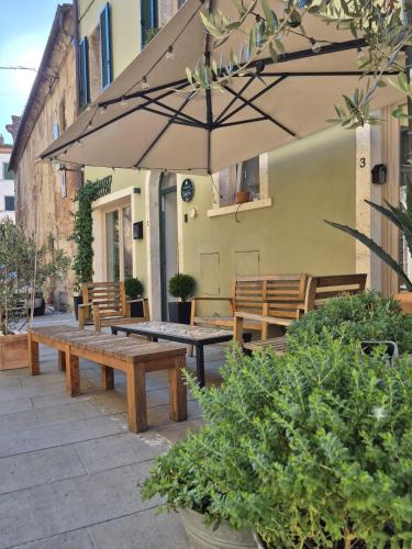 a patio with wooden benches and an umbrella at A Casa di BiaGio in Rapolano Terme