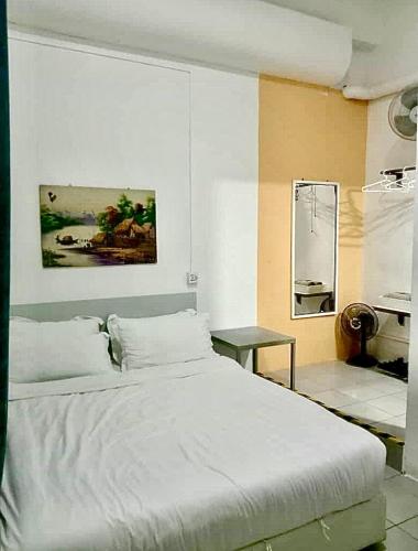 a bedroom with a large white bed and a table at Ozzy Lodge Semporna in Semporna
