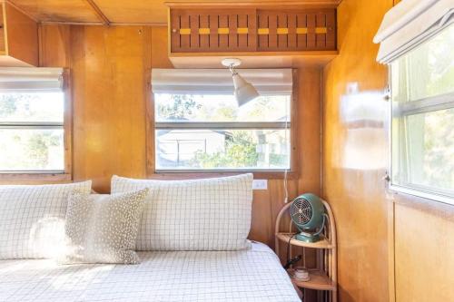 a bedroom with a bed with white pillows and two windows at Vintage Spartan-retro Farm Stay W Ev Charger in Arroyo Grande