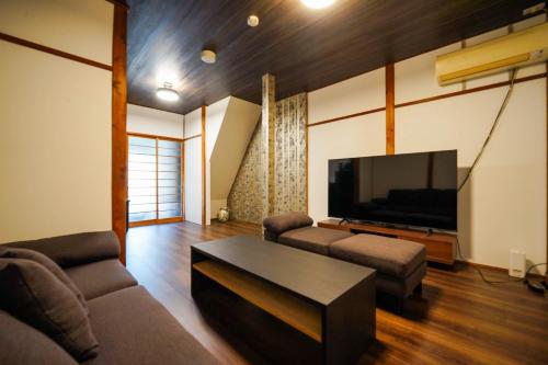 a living room with a couch and a flat screen tv at Guest House WASSO in Kyoto
