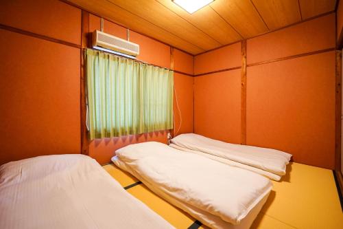 two beds in a small room with a window at Guest House WASSO in Kyoto