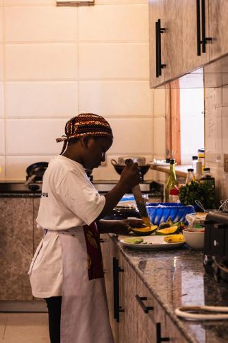 a woman standing in a kitchen preparing food at Mem Luxury Apartments and Hotel in Paje