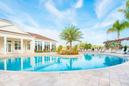 a swimming pool with palm trees and a house at Great and practical townhouse in gated community, sleeps 6 10 min to Disney! in Orlando