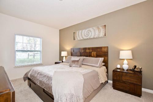 a bedroom with a bed and two lamps and a window at Great and practical townhouse in gated community, sleeps 6 10 min to Disney! in Orlando