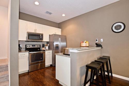a kitchen with white cabinets and a counter with stools at Great and practical townhouse in gated community, sleeps 6 10 min to Disney! in Orlando