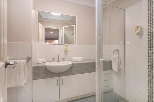 Un baño blanco con lavabo y ducha. en HME Collection Margaret River Townhouse 2, en Margaret River Town