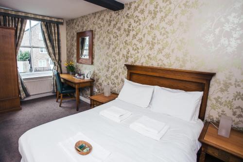 a bedroom with a white bed and a desk and a window at Waggon and Horses in York