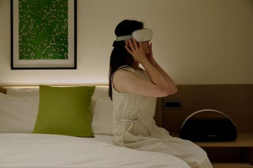 a woman sitting on a bed drinking a cup of coffee at Sowon Ryokan and Hotel by Aank Sangbong in Seoul