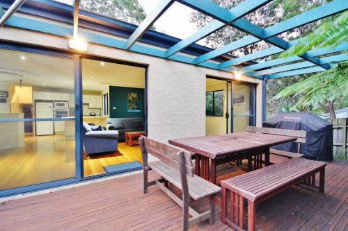 a wooden deck with a wooden table and benches at Sand Water at Hyams Beach in Hyams Beach