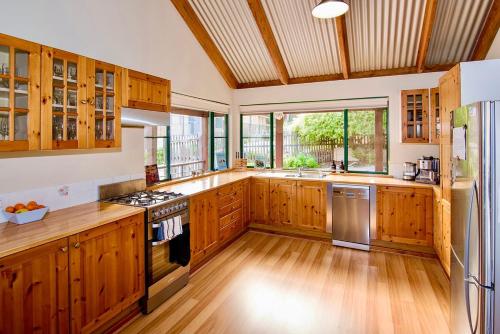 a large kitchen with wooden cabinets and stainless steel appliances at The Tree House Dunsborough in Dunsborough